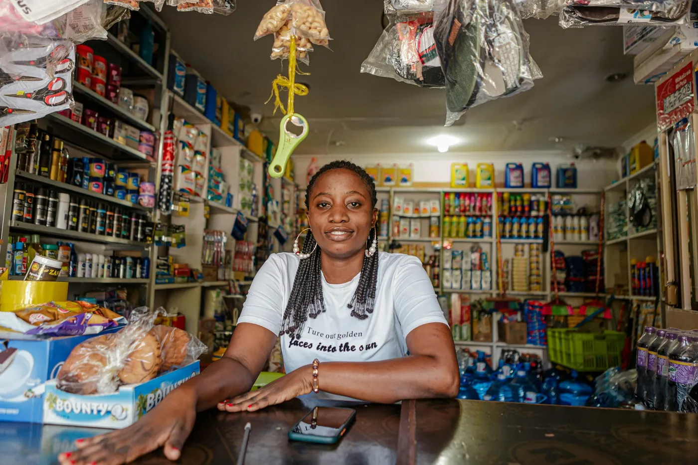Shopkeeper at her counter smiling at her phone